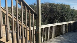 Une terrasse en bois avec une rambarde en métal et un lampadaire.