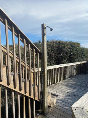 Una terraza de madera con barandilla de metal y un farol.