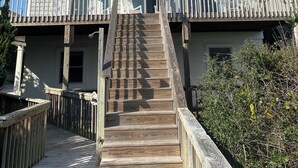 Une maison à deux étages avec une terrasse en bois et un balcon.