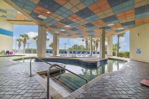 A pool area with a tiled floor, a pool, and lounge chairs.