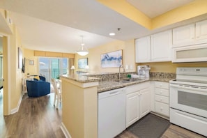 A modern kitchen with white cabinets, a granite countertop, and a built-in oven.