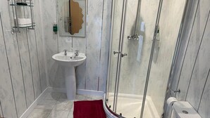 A bathroom with a glass shower enclosure, a sink, and a toilet. - Red Rose Hotel (Blackpool)