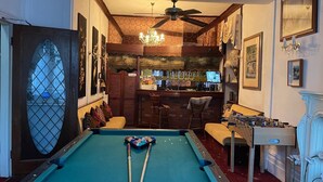 A pool table with two cues, a bar area with a television, and a seating area with a sofa and chairs. - Red Rose Hotel (Blackpool)