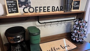 Un bar à café avec une enseigne indiquant « BAR À CAFÉ », une machine à café, une machine Keurig, un porte-tasses et une pancarte sur laquelle est écrit « SERVIETTES DE SPA ».