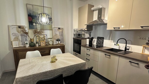 A modern kitchen with a dining area, featuring a table with chairs, a hanging light fixture, and a microwave. - GOLD APARTMENT**** in the heart of Pula only 5 minutes from the sea (Pula)