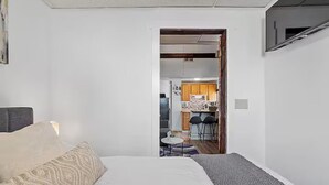 Un dormitorio con una cama, una mesita de noche y una pequeña mesa con sillas en la habitación contigua.