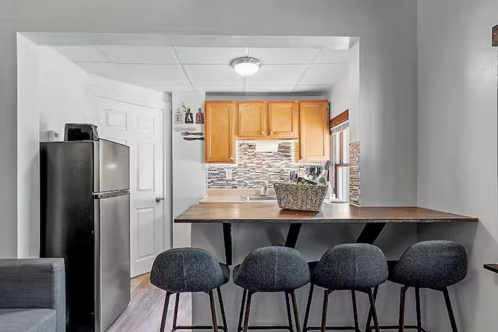 A modern kitchen with a central island, wooden cabinets, and a black refrigerator.