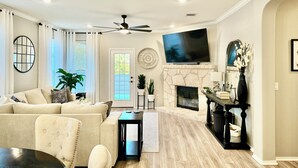 Una sala de estar con chimenea, televisor y ventilador de techo.