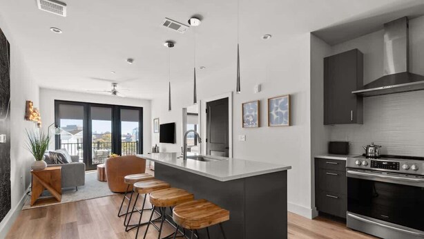 A modern kitchen with a central island, bar stools, and a large window.