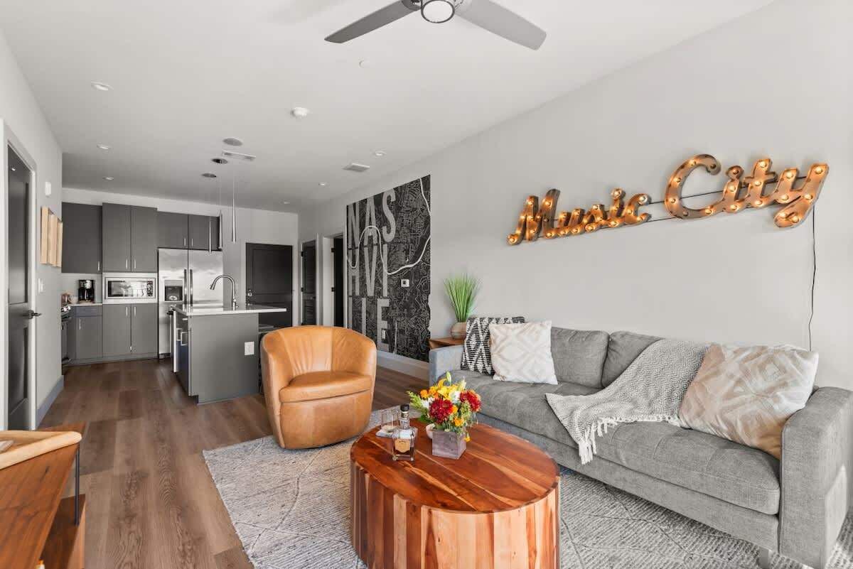 A modern living room with a grey sofa, a wooden coffee table, and a leather armchair.