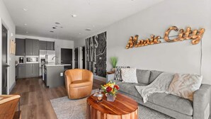 A modern living room with a grey sofa, a wooden coffee table, and a leather armchair.