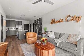 Uma sala de estar moderna com um sofá cinzento, uma mesa de centro de madeira e uma poltrona de couro.