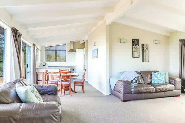 Un espacio habitable amplio con un sofá, una mesa de comedor con sillas y una zona de cocina.