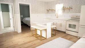 Une cuisine moderne avec des meubles blancs, un plan de travail blanc et un tabouret de bar à cadre doré.