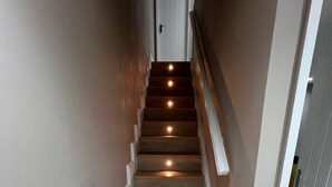 A wooden staircase with white trim, leading to a door at the top.