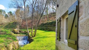 A stone building with a small waterfall and a grassy area.