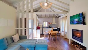 A spacious living area with a high ceiling, a sofa, a dining table, and a fireplace.