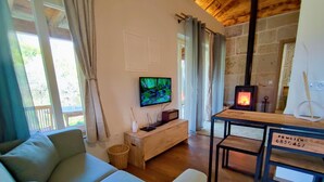 Uma sala de estar acolhedora com um sofá, uma televisão, uma lareira e uma parede de pedra.