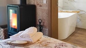 Um quarto com lareira a lenha, uma banheira e toalhas dobradas sobre uma mesa.