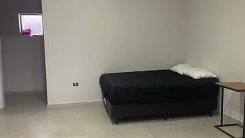 Una habitación con cama, una mesita y una puerta con ventana.