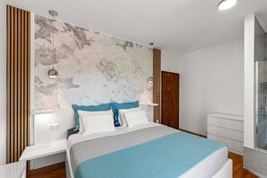 A modern bedroom with a large bed, a wooden panel wall, a patterned headboard, and a glass shower enclosure.