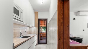 A modern kitchen with a built-in oven, a wooden countertop, and a view into a stone fireplace area.