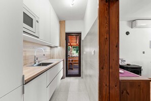 A modern kitchen with a built-in oven, a wooden countertop, and a view into a stone fireplace area.