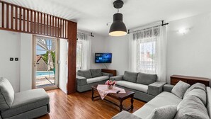 A modern living room with a grey sofa set, a wooden coffee table, and a flat-screen TV mounted on the wall.
