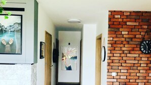 Ein Flur mit Kamin, einem gerahmten Gemälde, einer Ziegelwand und einer Uhr.
