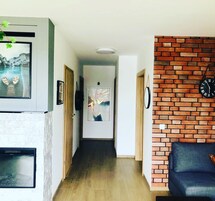 Un pasillo con chimenea, un cuadro enmarcado, una pared de ladrillo y un reloj.