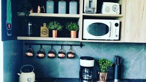 Eine Küche mit Mikrowelle, Kaffeemaschine, Wasserkocher und hängenden Töpfen.