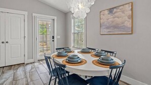A dining area with a round table, chairs, and a chandelier. - 5 Min Stroll to Beach in PCB: Gm Rm+Put Grn+Yard! (Panama City Beach)