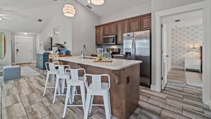 A modern kitchen with a central island, bar stools, stainless steel appliances, and pendant lighting. - 5 Min Stroll to Beach in PCB: Gm Rm+Put Grn+Yard! (Panama City Beach)