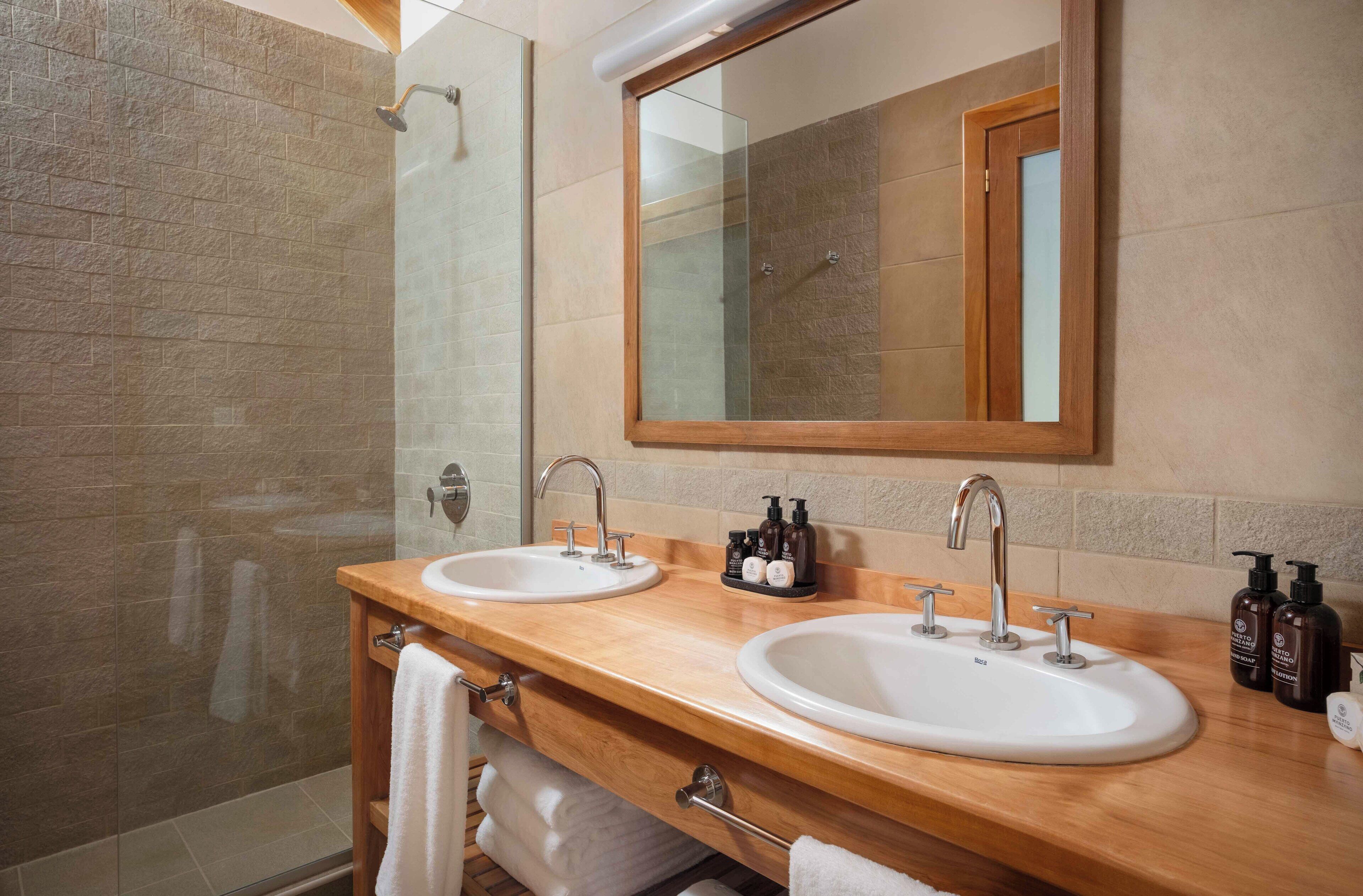 Un baño con dos lavamanos, un espejo grande y una zona de ducha.