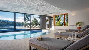 Una piscina interior moderna con sillones de descanso y vistas a las montañas.