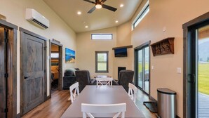 A modern interior with a dining area, a ceiling fan, and a TV mounted on the wall.