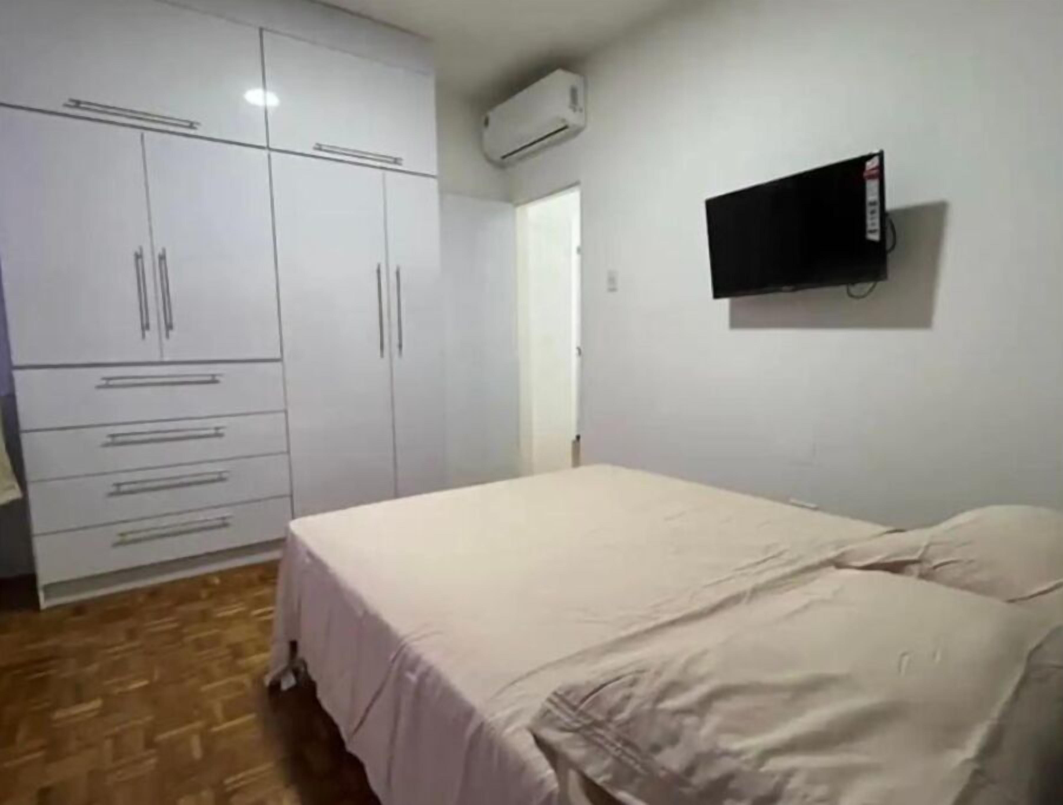 Un dormitorio con cama, armario, televisor de pantalla plana y aire acondicionado.