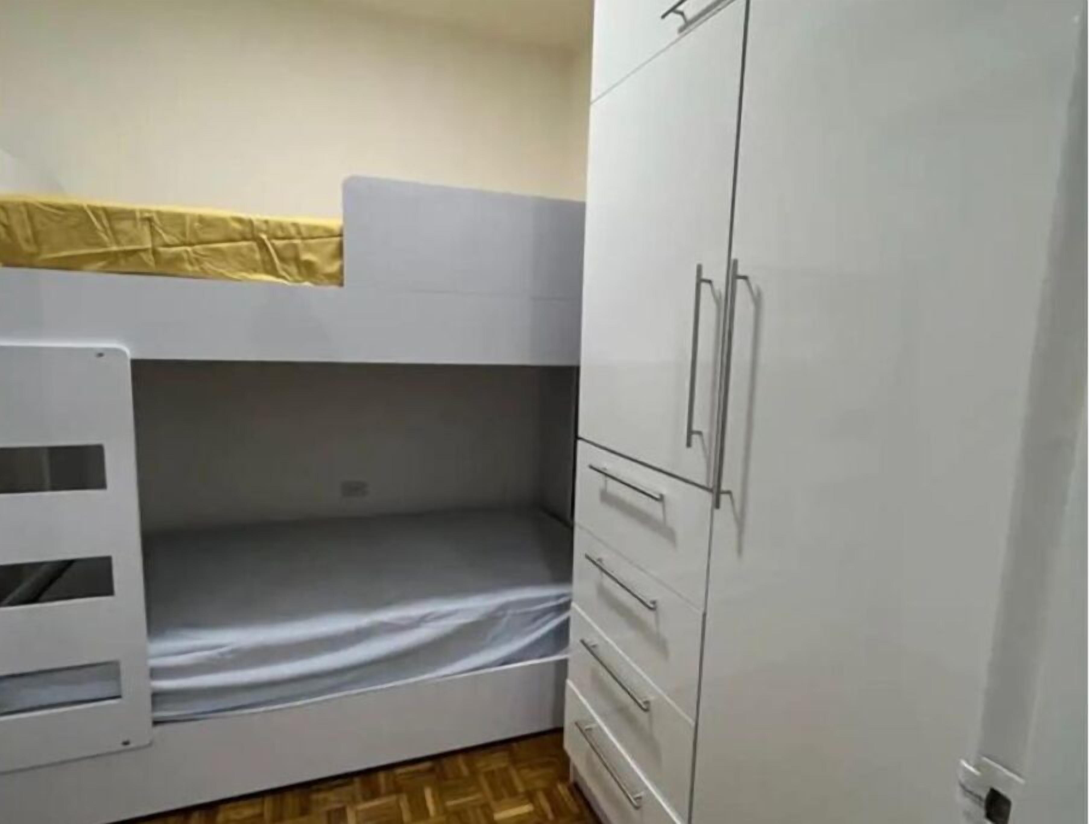 A bunk bed with a lower bunk and a wardrobe with multiple drawers.
