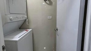 Een wasserette met een wasmachine en droger, een deur en een wandcontactdoos.