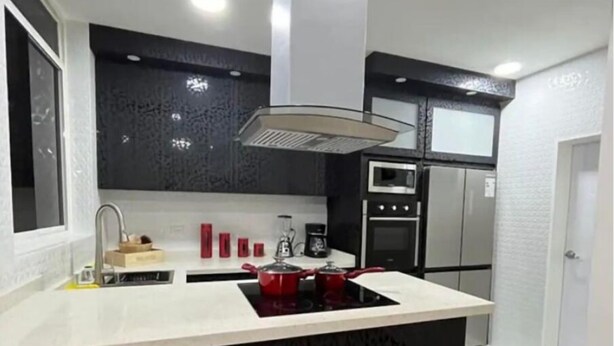 Een moderne keuken met een centraal eiland, een zwarte achterwand, roestvrijstalen apparatuur en een raam.