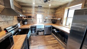 A modern kitchen with wooden walls, a stainless steel refrigerator, a built-in oven, and a dishwasher.