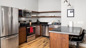 A modern kitchen with stainless steel appliances, wooden cabinets, and a central island.