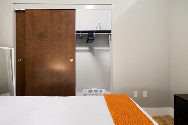 A bedroom with a bed, a wooden wardrobe, a white wall, and a small black nightstand. - Chic Loft in Peoria Warehouse District (Peoria)