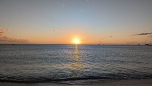 Ein Sonnenuntergang über einem ruhigen Meer mit Booten und klarem Horizont.