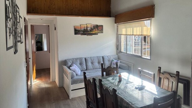A cozy dining area with a wooden table and chairs, a cushioned bench, and a window with blinds. - Your perfect stay here, with grill, private garage and wifi, centrally located. (Neuquén)