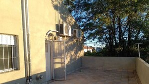 A rooftop terrace with tiled flooring, a metal gate, and air conditioning units. - Your perfect stay here, with grill, private garage and wifi, centrally located. (Neuquén)