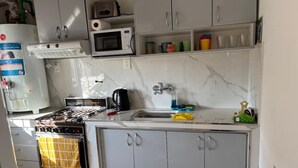 A compact kitchen with a stove, microwave, and sink. - Your perfect stay here, with grill, private garage and wifi, centrally located. (Neuquén)