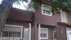 A two-story building with a brown facade, white-framed windows, and a metal gate. - Your perfect stay here, with grill, private garage and wifi, centrally located. (Neuquén)