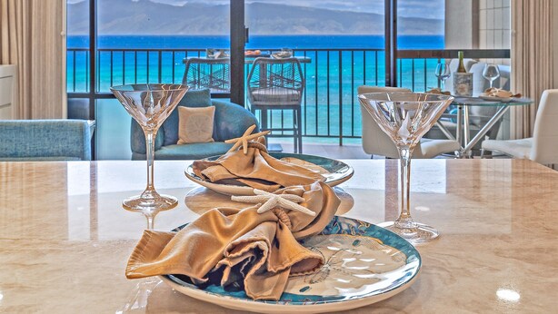 Une table recouverte d’une nappe décorative, deux verres à martini et une assiette aux motifs bleus et blancs.