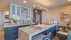 Une cuisine moderne dotée d’un îlot central, de meubles de rangement intégrés et d’un réfrigérateur.